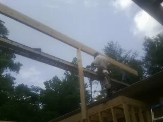 Carpenter setting a ridge beam over a new addition frame — Ice Dam Removal by Roofing Brothers in Check