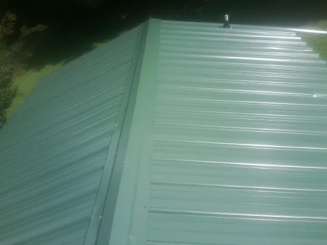 New green metal panels meeting at the ridge of a roof — Flat Roof Repair work by our crew in Check