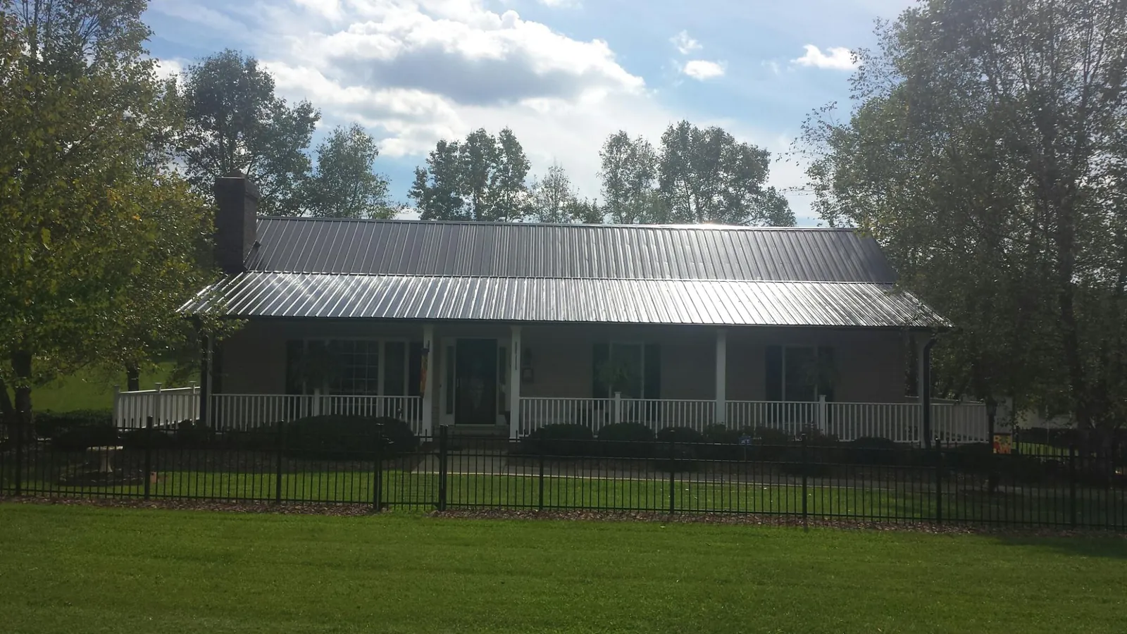 Gray metal roof on a brick ranch with a full width front porch — Gutter Guard Installation work by our crew in Check