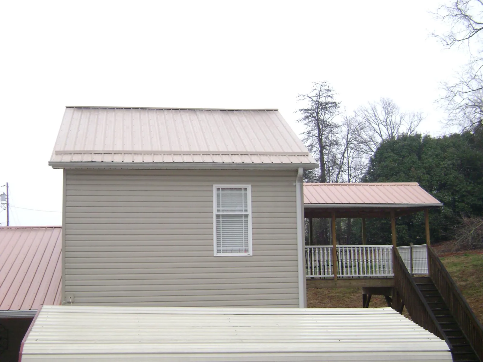 Tan metal roofs on a two story addition and attached porch, from a Roof Replacement job in Check